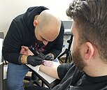 A Catholic deacon receiving a tattoo at Razzouk