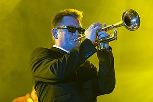 Smash standing onstage, playing a trumpet