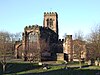 The apse of a stone Gothic church with the tower beyond