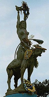 Statue of María Lionza with various wreaths and beads decorating it from top to base.