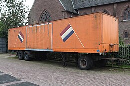 Oranje autonome aanhangwagen geparkeerd achter een kerk