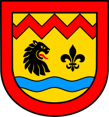 A coat of arms depicting the head of a black animal with an open mouth showing to a black lily shaped symbol. In the bottom half is a blue horizontal stripe and in the top a red horizontal zigzag. The background is yellow and it has a red frame.