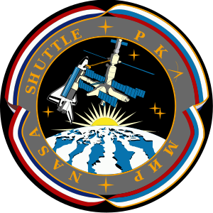 An illustration showing a space shuttle docked to a space station above a stylized version of the Earth. The Sun is rising over the Earth, and the image is surrounded by ribbon in red, white and blue. The words NASA, Shuttle, РКА and Мир are written around the image.