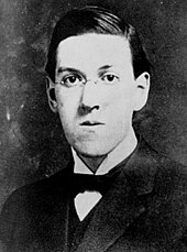 Kopfporträt von H.P. Lovecraft in schwarz-weiß; er blickt direkt in die Kamera und trägt eine gerundete Brille, das dunkle Haar ist seitlich gescheitelt. Bekleidet ist er mit einem dunklen Anzug, einem weißen Hemd und einer dunklen Fliege.