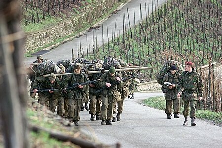 (2002) Soldaten tijdens de AMOL dragen op een geïmproviseerde brancard een collega naar boven over een steile weg tussen de wijnranken aan de Moezel.