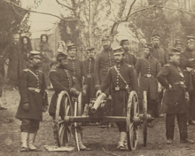 Sepia-toned photo shows several Union soldiers of the 96th Pennsylvania Infantry posing next to a small caliber cannon.