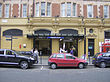 A gold-coloured building with a rectangular, dark blue sign reading "QUEENSWAY STATION" in white letters and people walking in front