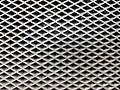 Textur eines Lochblechs (Computer-Lufteinlassgitter) aus Metall mit rautenförmigen Öffnungen.