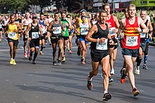 Frontale Farbfotografie von Marathonläufern mit ihren Startnummern in einer Straße.