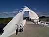 View through the curved arch structure of a steel bridge, with a mountain in the background