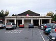 A red-bricked building with "BRENT CROSS STATION" written on it and light grey pillars making up the facade all under a blue sky with white clouds