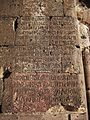 An inscription on the exterior wall near the main entry. Note the stonemasons mark on the fourth line down.