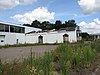 Zuivelfabriek: kantoor, fabrieksgebouw met tussenlid, machinehal en schoorsteen.