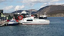 Bildet viser hvordan Stokmarknes har en naturlig havn, med hurtigbåtkai, museum for Hurtigruten, hurtigrutekai, gammel fergekai og offentlig marina.