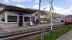 Red and white train at a train station next to a platform shelter