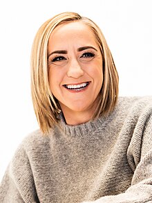 Head shot of Caine smiling and wearing a grey shirt