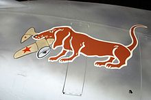 A painting of a dachshund holding a Soviet aircraft in its mouth.