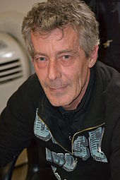 A grey-haired man smiling slightly