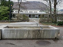 Sekundarschule Liestal. Widmann-Brunnen, Relief «Der Heilige und die Tiere». Eingeweiht am 6. Nov. 1961. Das Relief ist heute nicht mehr am Brunnen zu sehen.