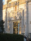 Photograph of a grand entry door at the Hearst San Simeon Estate, with a great quantity of carved stonework, illuminated in the golden evening sun.