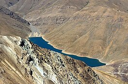 A small blue lake nestled between dry, rocky mountains.