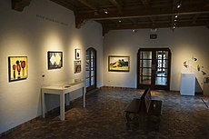 The Peggy Pitman Mays Gallery at the McNay Art Museum, with five paintings and a sculpture on display, and two benches in the middle of the room.