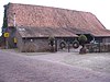 Huis met zadeldak tussen topgevels met vlechtingen. Tuinmuur met poortje