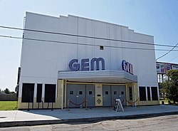 Large light gray building with metal marquee and two "GEM" signs in blue neon