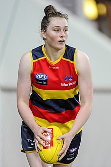 A female athlete with brown hair in a bun holding a football