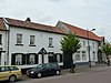 Bakstenen huis met houten kozijnen en koetspoort