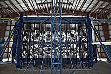 Viewed from the rear, a supporting frame for 12 large fans inside a hangar