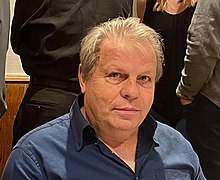 Porträtfoto von Martin Gross vom 3. Oktober 2022. Der porträtierte trägt ein blaues Hemd und schaut direkt und aufmerksam in die Kamera.