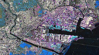 Satellitenaufnahme der Tsunamischäden im Hafen von Sendai vom 12. März 2011 (magenta: Trümmer; blau: Überschwemmungen)