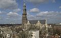 Seitliche Farbfotografie in der Obersicht einer braunen Kirche mit weißen Ornamenten um das Kirchenschiff und den Dachgiebeln. Der Turm mit goldener Haube und Dachlaterne steht links.