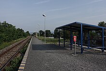 A view of the temporary stop consisting of a sheet metal shelter and a boarding edge, the ground is covered with fine gravel