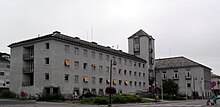 Foto eines grauen Bürogebäudes mit einem kleinen Turm