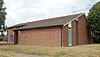 Three-quarter view of a modern L-shaped brick building with a blank wall on the shorter side.