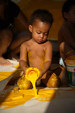 Sarı boyayla oynayan bir çocuk