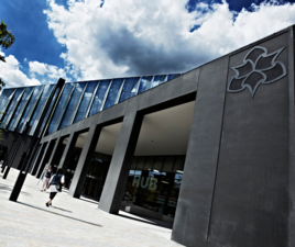 Manchester Metropolitan University Business School front entrance. The main front doors are pictured with the University logo prominent at the front of the image.