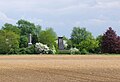 Blick über ein flaches Feld im Frühling 2014 mit dem Denkmal für die Hannoveraner und dem Gordon-Denkmal