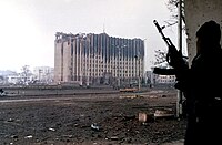 A Chechen fighter stands near the government palace building during a short lull in fighting in Grozny, Chechnya.