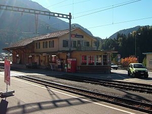 Two-story building with gabled roof next to double-track railway line and side platforms