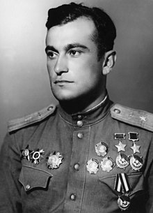 1945 formal postwar portrait of a handsome young major (Amet-khan Sultan) in parade dress of the Soviet Air Forces looking off into the distance. He is seen wearing his two hero of the Soviet Union medals, three orders of Lenin and three orders of the red banner on one side of his chest (right side in photo, left in life) and his Order of the Red Star, Order of the Patriotic War, and Order of Aleksander Nevsky on the other side.