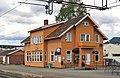 Foto eines orange gestrichenen hölzernen Bahnhofsgebäudes