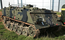 Colour photo of a tracked military vehicle painted in green and black camouflage