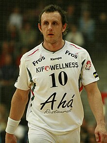 Schnuchel stands wearing a white shirt and looks off while standing on a court.