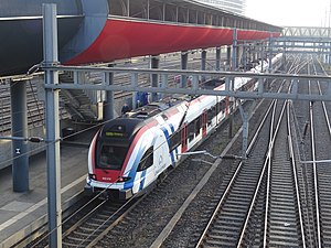 Red-colored enclosed walkway above single side platform