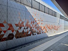 Concrete retaining wall with orange-red coloured triangles inscribed on it