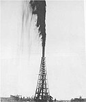 Example of an early 20th century oil drilling derrick showing an oil strike