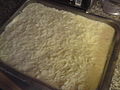 Η κρέμα μπεσαμέλ απλώνεται πάνω στο ταψί. Η επιφάνεια μπορεί προαιρετικά να πασπαλιστεί με τριμμένο τυρί ή τριμμένη φρυγανιά πριν το ψήσιμο.